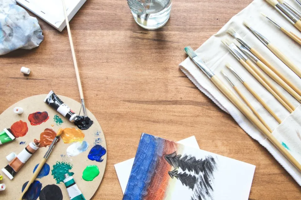 Pinturas y pinceles sobre una mesa de trabajo